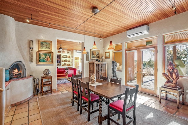 dining area with a wall mounted AC, a fireplace, light tile patterned flooring, wooden ceiling, and french doors