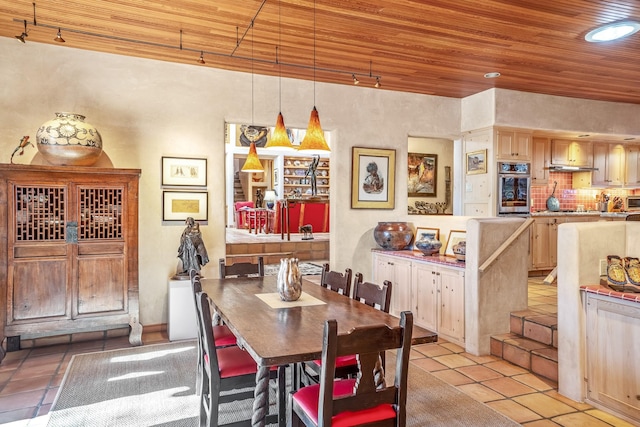 tiled dining area featuring track lighting and wooden ceiling