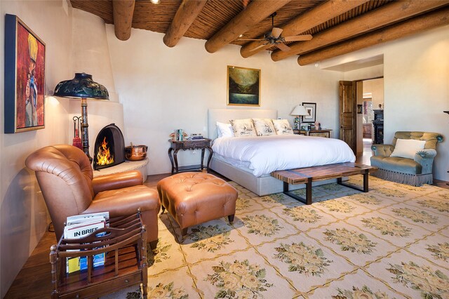 bedroom with beam ceiling, wood ceiling, a fireplace, and light hardwood / wood-style floors