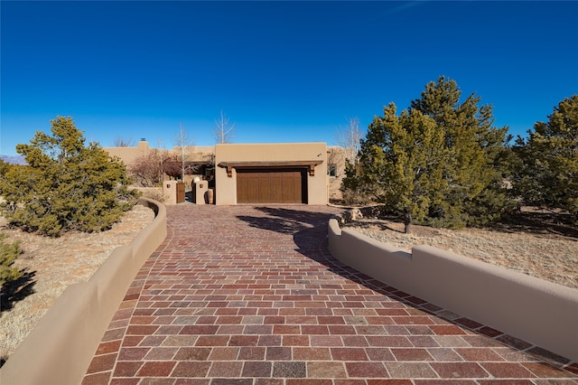 pueblo-style house with decorative driveway and an attached garage