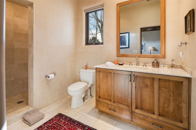 bathroom with tiled shower, vanity, toilet, and tile patterned flooring