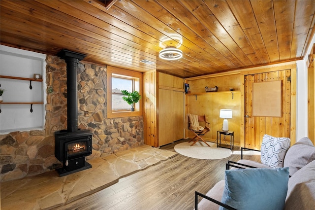 living room with wooden ceiling, a wood stove, wood finished floors, and visible vents