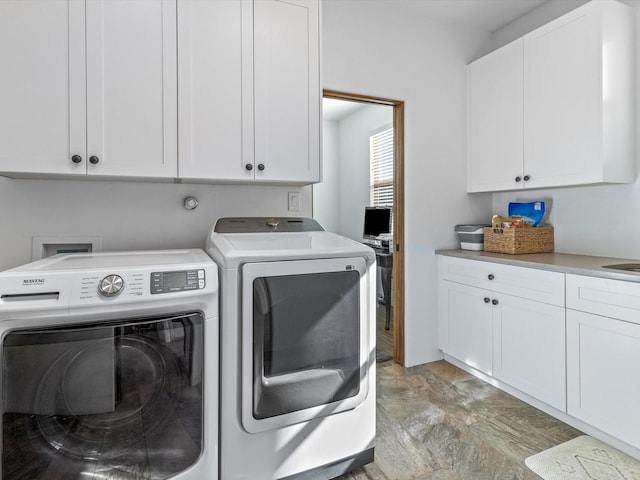 clothes washing area with cabinets and washing machine and clothes dryer