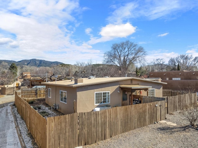 view of front of property with fence private yard, a mountain view, and stucco siding