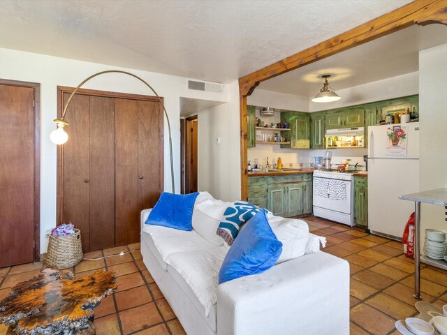 kitchen featuring decorative light fixtures, sink, green cabinets, light tile patterned floors, and white appliances