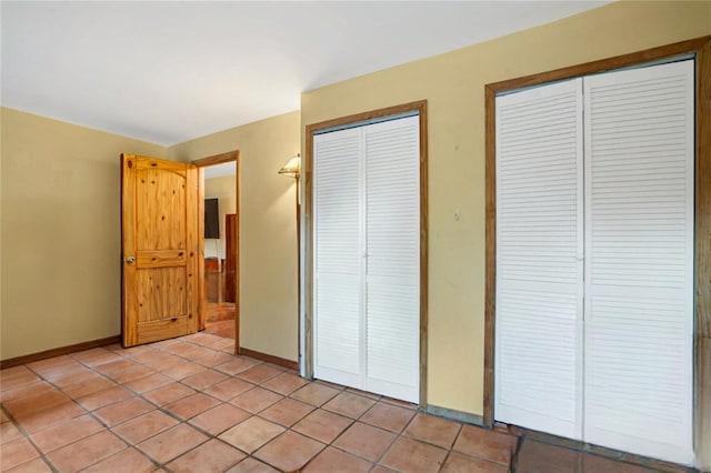 unfurnished bedroom featuring light tile patterned floors and two closets