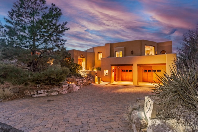 pueblo revival-style home with a garage and a balcony