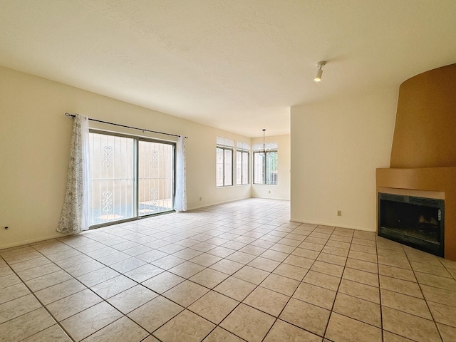 unfurnished living room featuring light tile patterned flooring, a large fireplace, and a textured ceiling