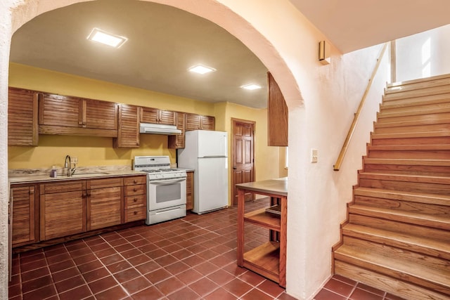 kitchen with white appliances, sink, and dark tile patterned floors