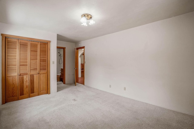 unfurnished bedroom with light colored carpet and a closet