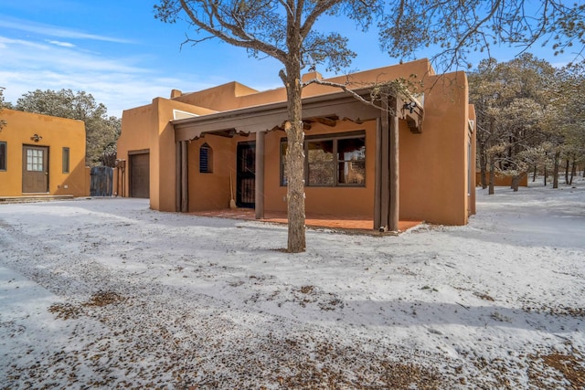 snow covered house featuring a garage