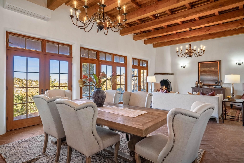 dining room featuring french doors, a wall mounted air conditioner, a notable chandelier, beamed ceiling, and a fireplace