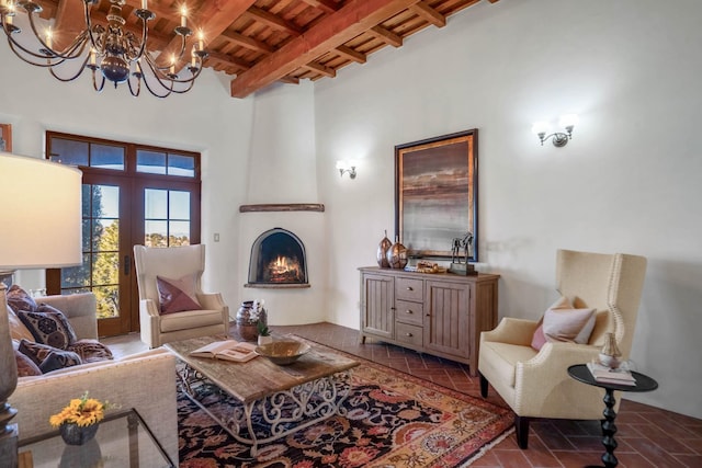 living room with beamed ceiling, a large fireplace, wood ceiling, an inviting chandelier, and french doors