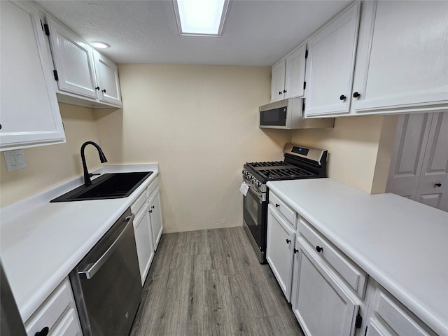 kitchen featuring hardwood / wood-style flooring, white cabinetry, appliances with stainless steel finishes, and sink