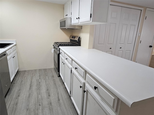 kitchen featuring stainless steel appliances, white cabinetry, and light hardwood / wood-style floors