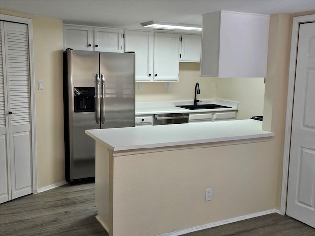 kitchen featuring appliances with stainless steel finishes, sink, dark wood-type flooring, and kitchen peninsula