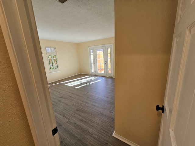 spare room featuring dark wood-type flooring and a textured ceiling