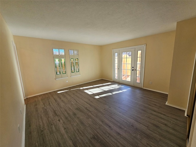 empty room with dark hardwood / wood-style floors, a textured ceiling, and a wealth of natural light