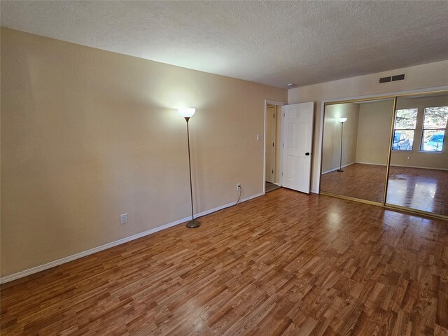 unfurnished bedroom featuring wood-type flooring and a textured ceiling