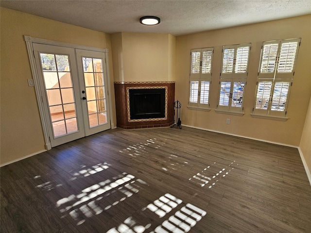 unfurnished living room featuring plenty of natural light, a textured ceiling, dark hardwood / wood-style flooring, and french doors