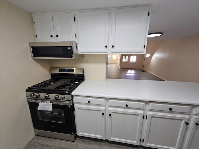 kitchen with white cabinetry, stainless steel appliances, and hardwood / wood-style floors