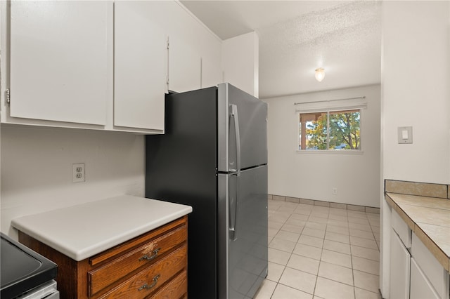 kitchen featuring stainless steel appliances, white cabinetry, light tile patterned floors, and a textured ceiling