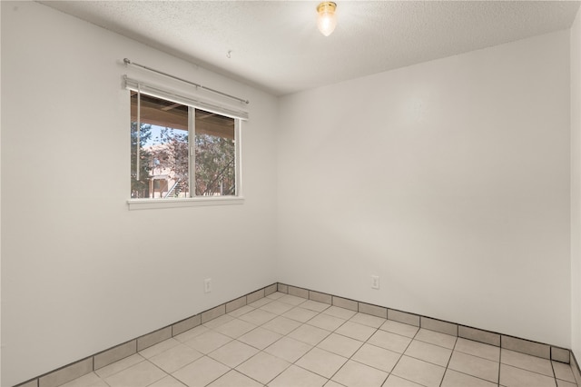 empty room with light tile patterned flooring and a textured ceiling