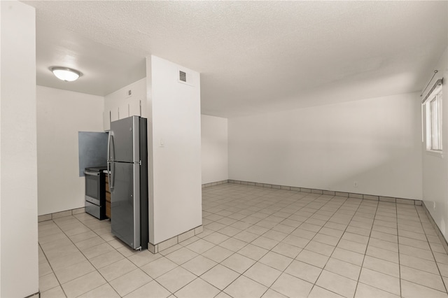 kitchen with light tile patterned floors, a textured ceiling, and appliances with stainless steel finishes