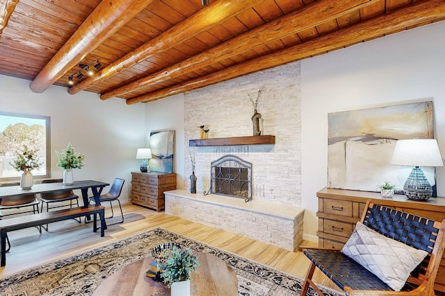 living room featuring light hardwood / wood-style flooring, a fireplace, wooden ceiling, and beamed ceiling