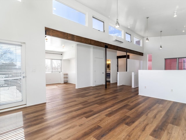 unfurnished living room featuring a barn door, dark hardwood / wood-style floors, and a high ceiling