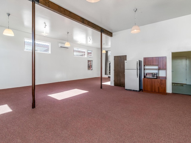 below grade area featuring a wall mounted air conditioner, carpet flooring, and freestanding refrigerator