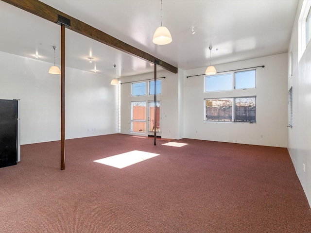 carpeted spare room with beamed ceiling and a high ceiling