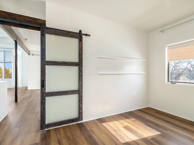 spare room featuring a barn door, plenty of natural light, and wood finished floors