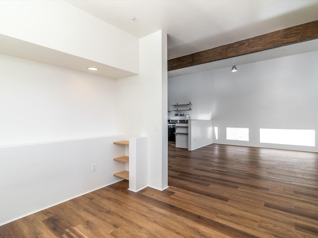 unfurnished room featuring dark wood finished floors and beam ceiling