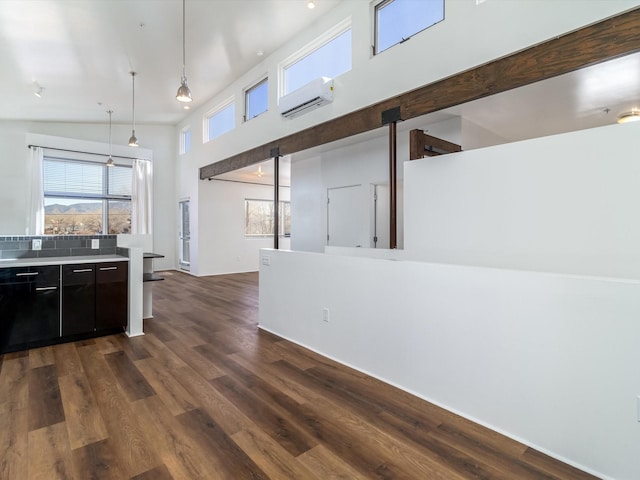 kitchen featuring a wall mounted AC, a high ceiling, dark wood-style flooring, light countertops, and dark cabinets