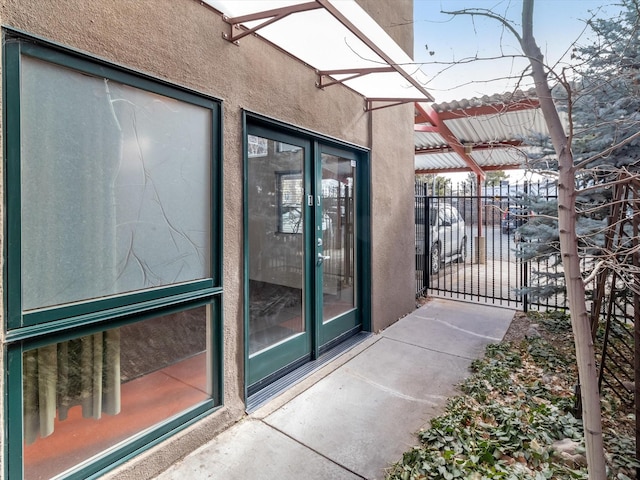 view of exterior entry featuring fence and stucco siding