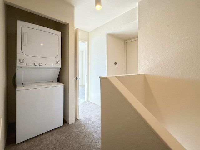 laundry room featuring stacked washer and clothes dryer and carpet