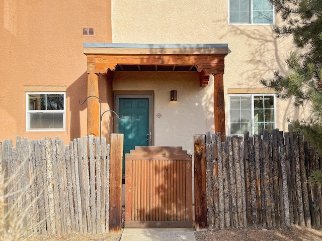2210 Miguel Chavez Rd Unit 815, Santa Fe, NM 87505 - doorway to property with a gate, stucco siding, visible vents, and fence