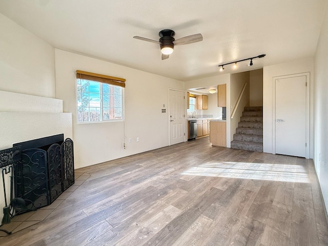 unfurnished living room featuring sink, ceiling fan, and light wood-type flooring