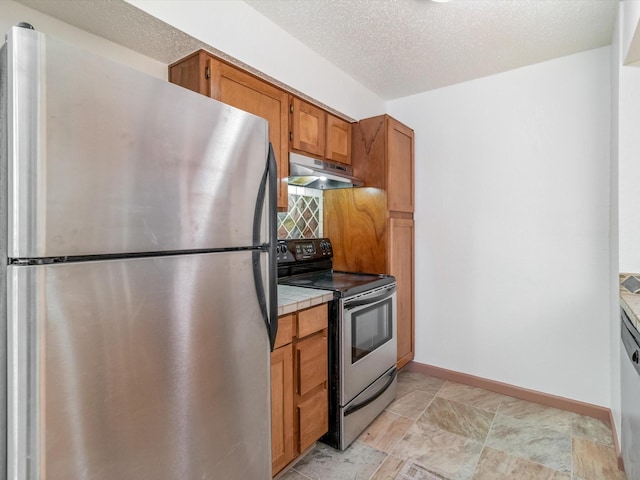 kitchen with appliances with stainless steel finishes, tile countertops, a textured ceiling, and backsplash