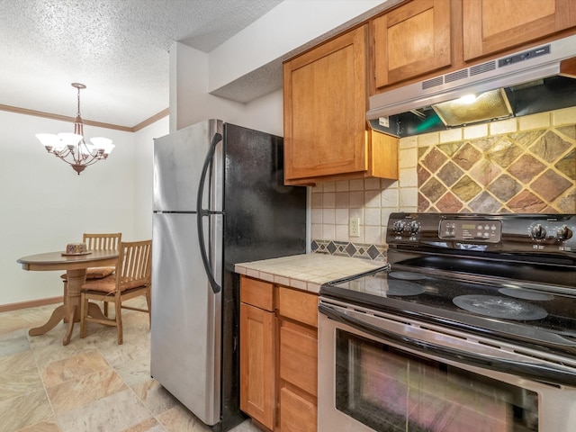 kitchen with stainless steel appliances, decorative backsplash, a textured ceiling, decorative light fixtures, and tile countertops