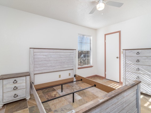 bedroom with ceiling fan and a textured ceiling