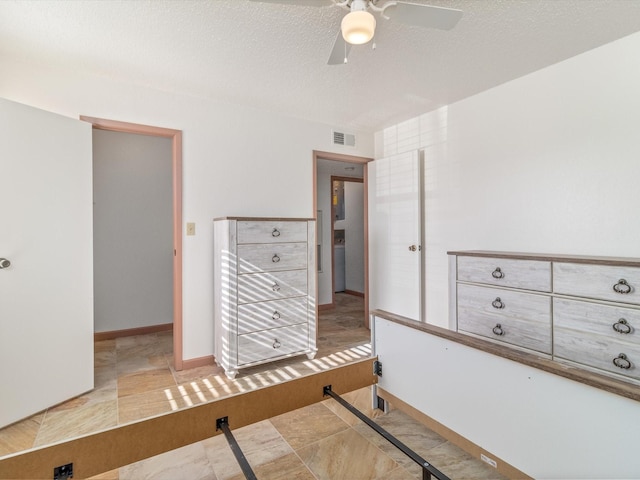 bedroom with ceiling fan and a textured ceiling