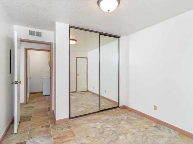 unfurnished bedroom with a textured ceiling and a closet