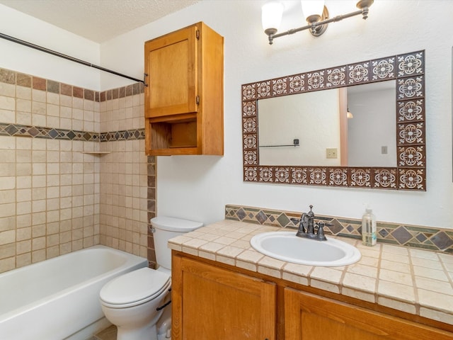 full bathroom with vanity, tiled shower / bath, toilet, and a textured ceiling