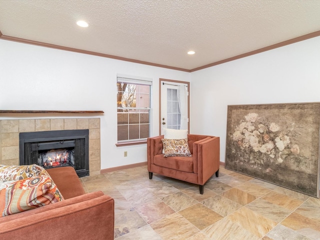 living room featuring a tiled fireplace, ornamental molding, and a textured ceiling