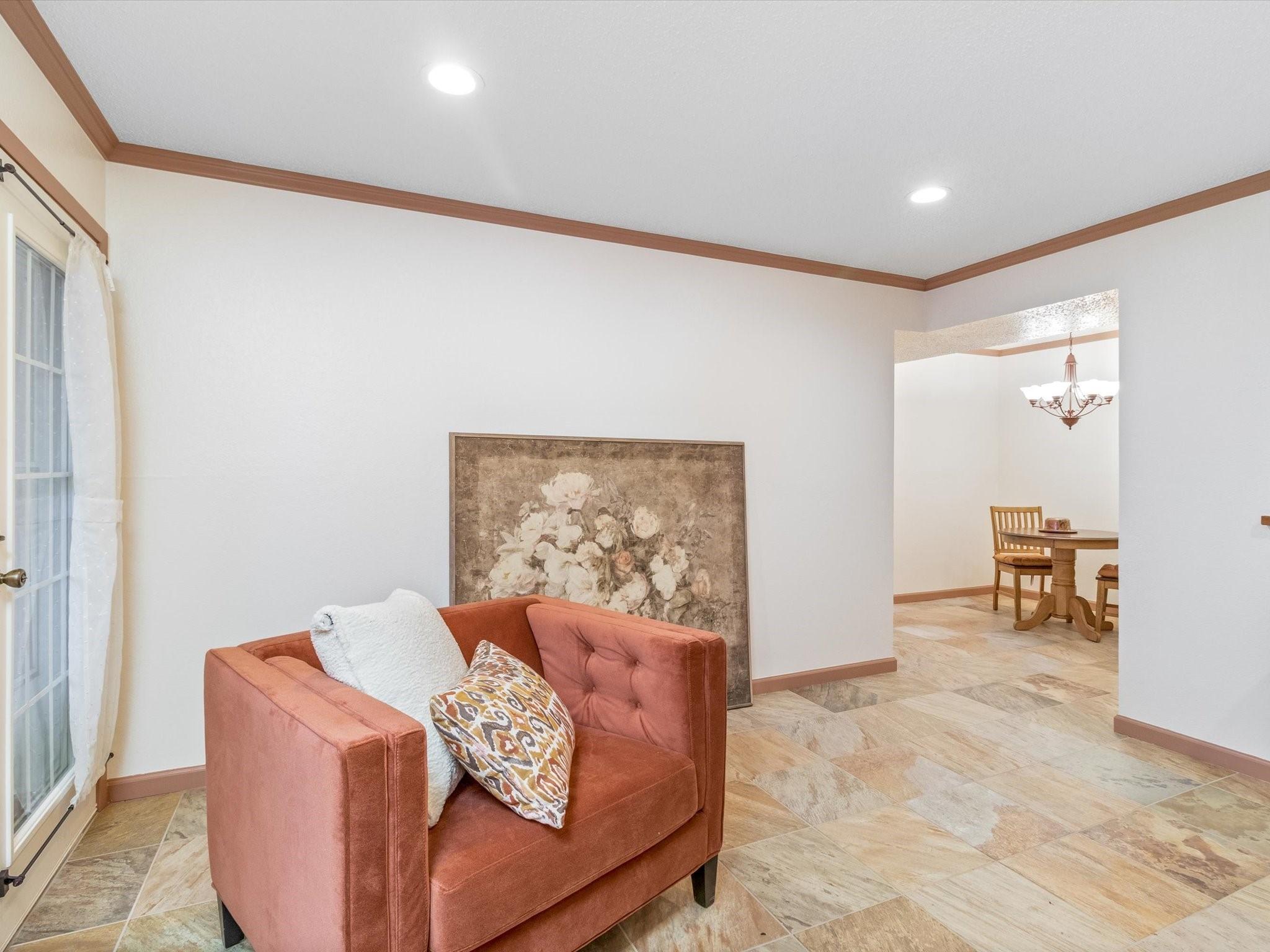 living area with crown molding and a chandelier