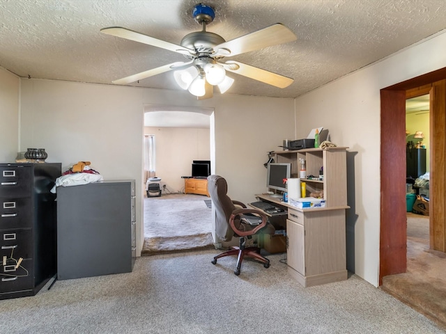 home office featuring ceiling fan, light carpet, and a textured ceiling