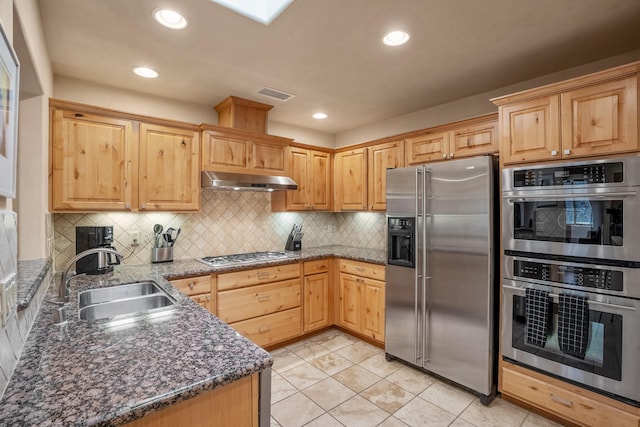 kitchen featuring sink, backsplash, stainless steel appliances, and dark stone counters