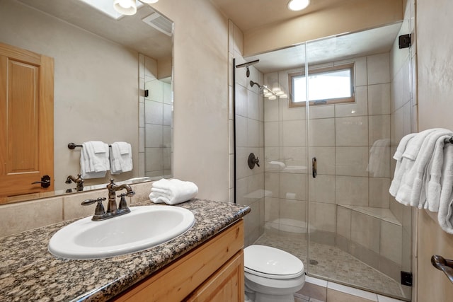 bathroom featuring vanity, a shower with door, and toilet